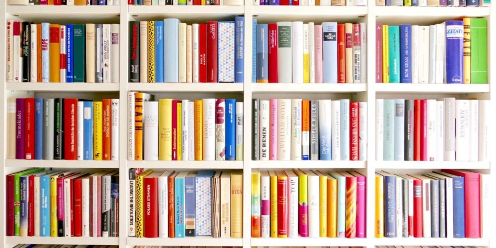 A large bookshelf filled with rows of colorful books, symbolizing an essential library of American history, politics, and religion books to read and protect against censorship and fascism.