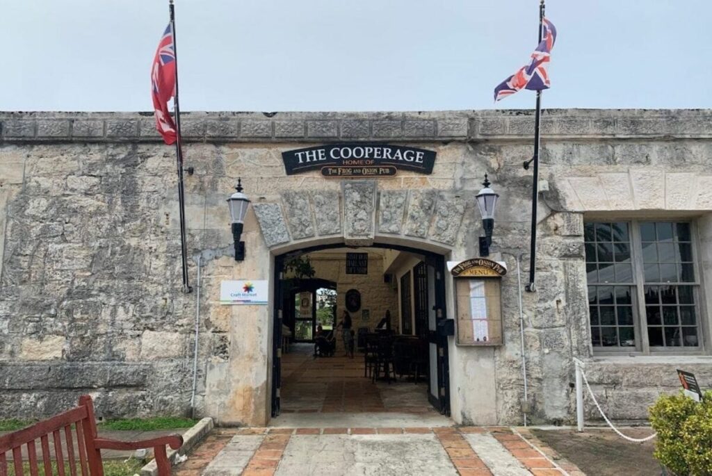 Entrance to 'The Cooperage' pub, flaunting historical charm with its stone facade and flanked by British flags, evoking a sense of traditional pub culture.