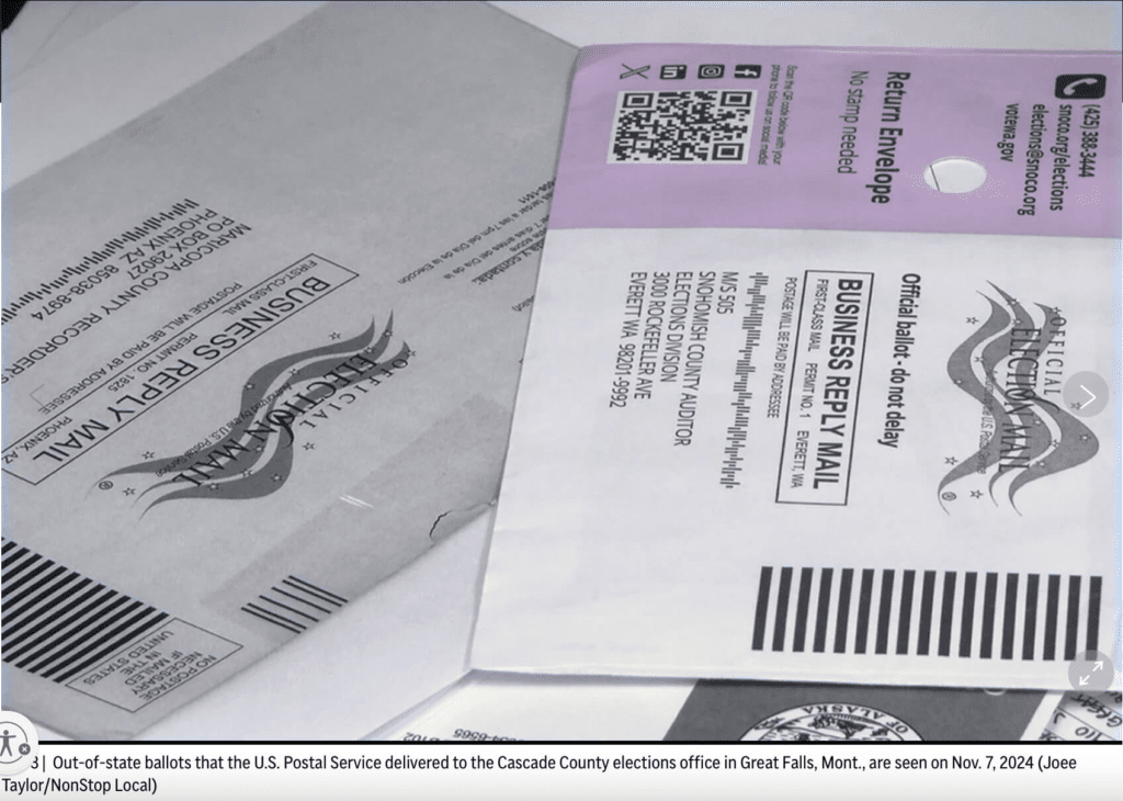 A close-up of multiple mail-in ballot envelopes, including an official election mail business reply envelope from Snohomish County, Washington. One of the envelopes is purple and labeled "Return Envelope," with a QR code and voter assistance information. The caption indicates that these are out-of-state ballots delivered to the Cascade County elections office in Great Falls, Montana, on November 7, 2024.