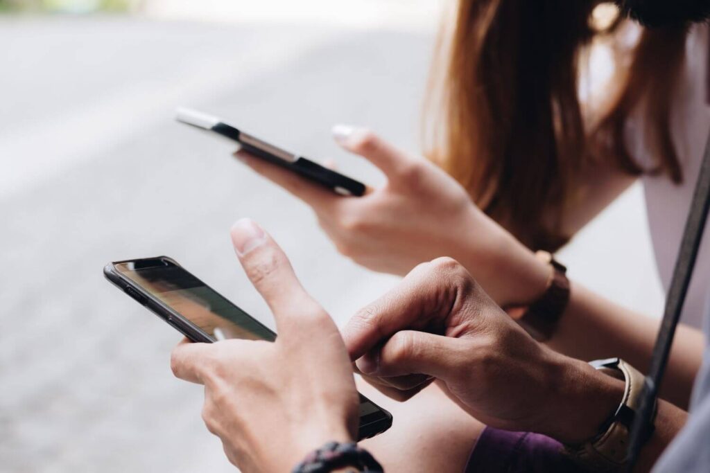 People scrolling on smartphones, representing information overload and political burnout from social media.