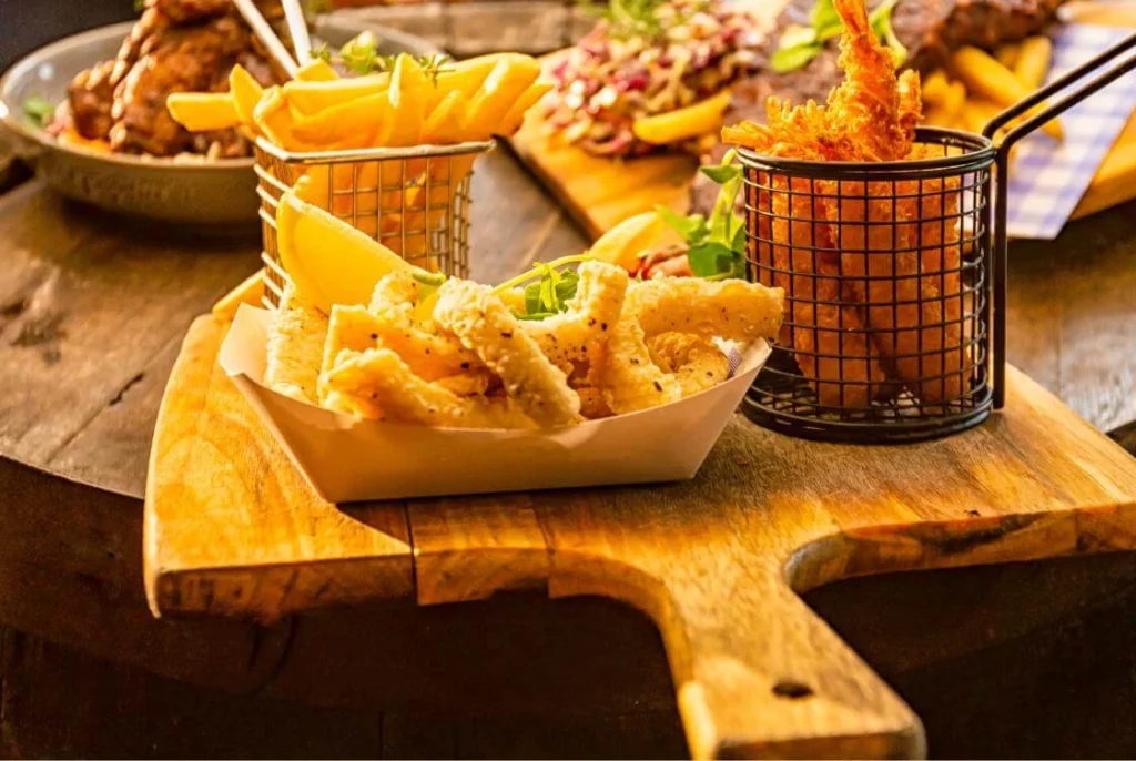 British pub sharing platter with chips, fried snacks, and dipping sauce on a wooden board. 