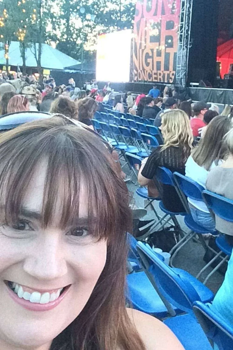 Gemma Lawrence alone and smiling with outside concert stage behind her.