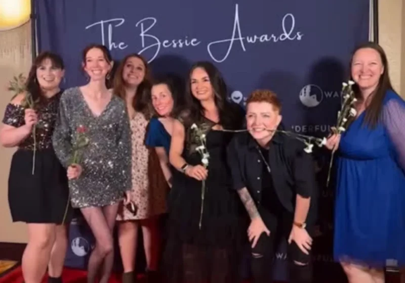 Gemma Lawrence, Hannah Dixon and five other women posing on the red carpet at the Bessie Awards, some holding white roses, in front of a backdrop with 'The Bessie Awards' text.