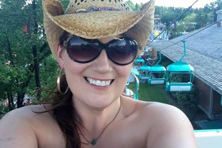 Gemma Lawrence takes a selfie wearing a straw cowboy hat and large sunglasses, smiling at the camera. The background shows WestJet Skyride chairs and the Stampede Midway.