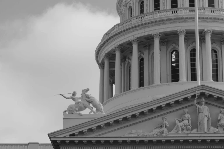 Close-up of the U.S. Capitol dome with classical warrior statue, evoking the aggressive symbolism often tied to authoritarian power structures.