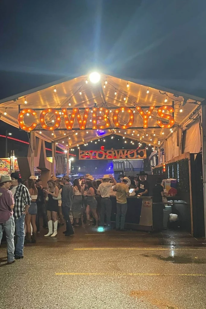 Bright marquee lights spell "Cowboys" above the packed entrance to the bar area at Cowboys Music Festival in Calgary.