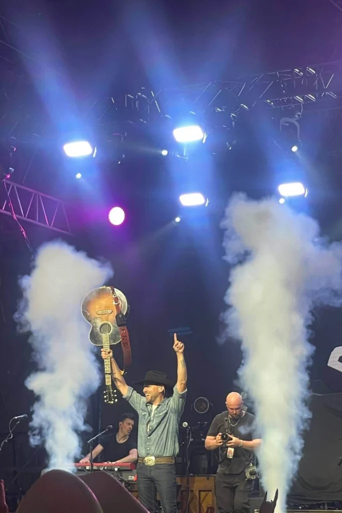 Country music performer lifting guitar on stage at Cowboys Music Festival in Calgary