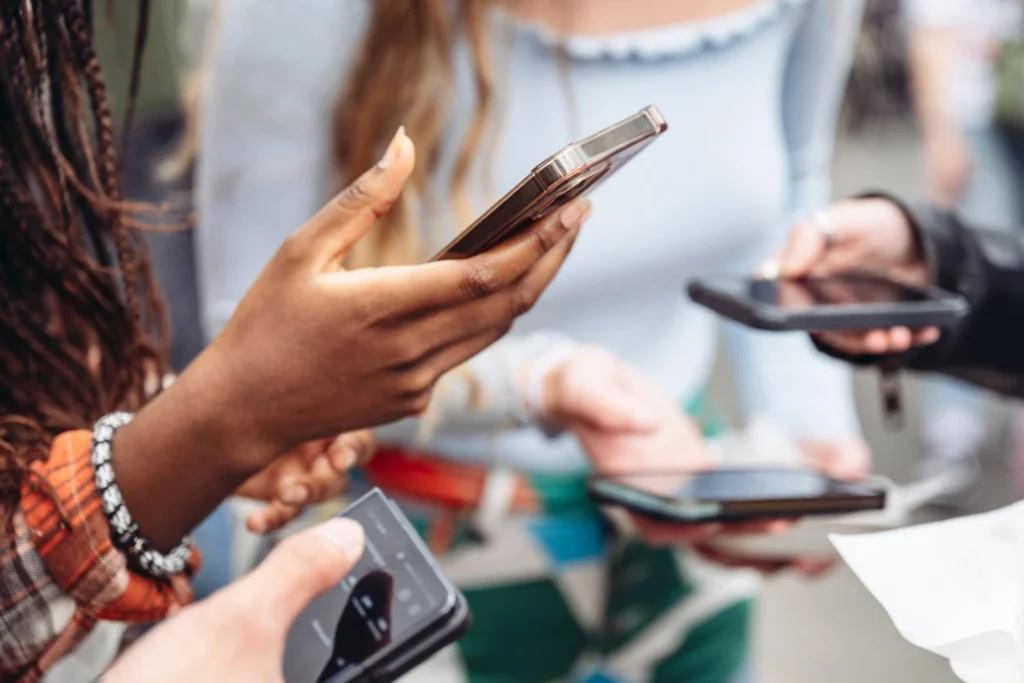 Close-up of diverse women using smartphones, symbolizing the collective power of female travelers to share, influence, and take action through digital platforms.
