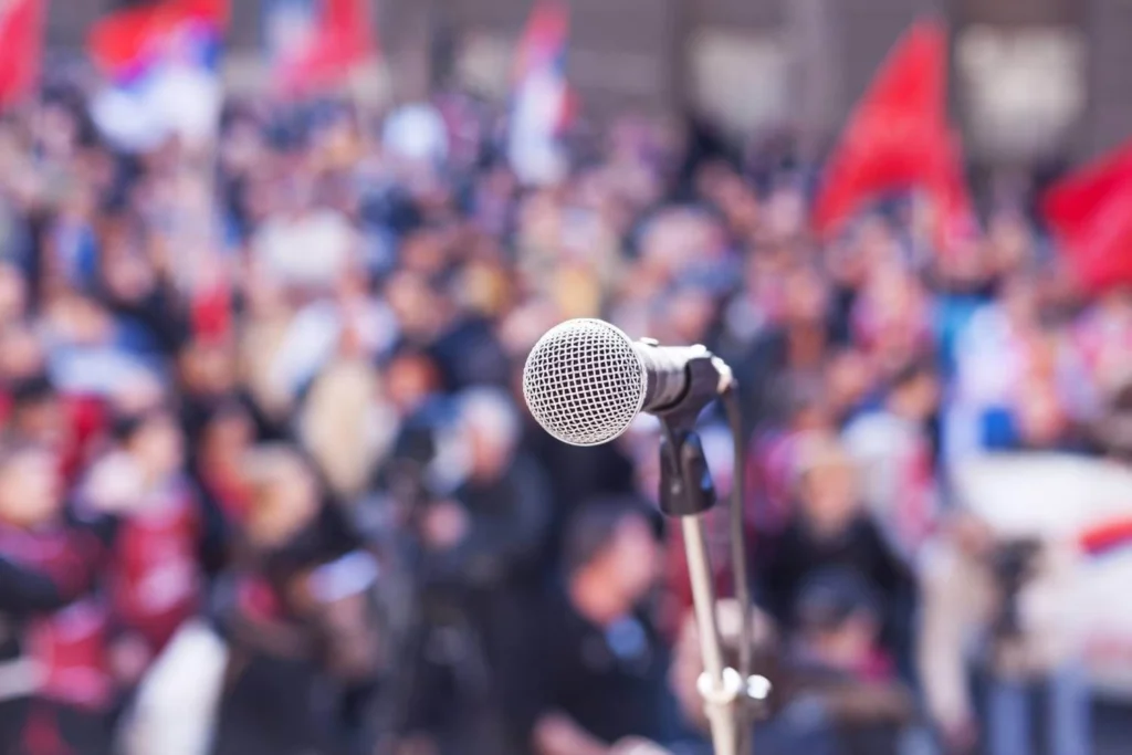 Close-up of microphone at a political rally, symbolizing how authoritarian leaders incite violence and unrest through charged rhetoric and public speeches.