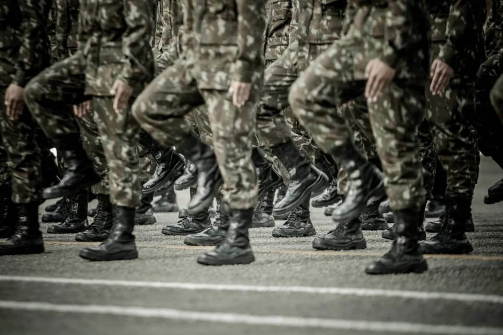 Soldiers in camouflage uniforms march in formation, illustrating the growing politicization of military power under authoritarian regimes and displays of force.