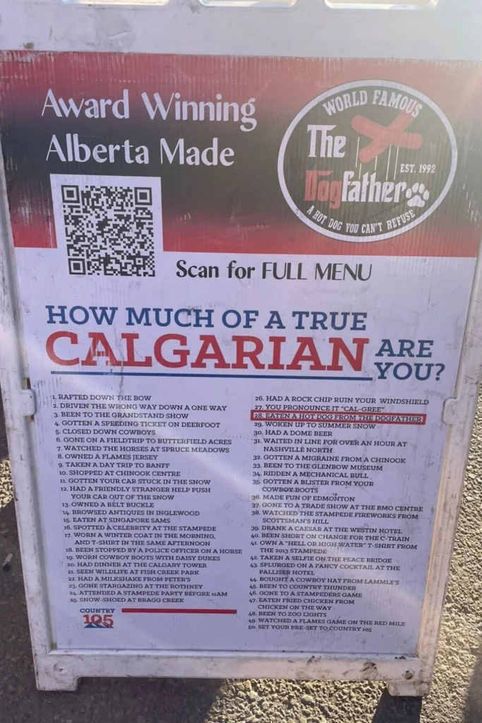 Fun Calgary checklist sign outside The Dogfather hot dog stand at Calgary Stampede listing 50 local experiences that make you a true Calgarian.