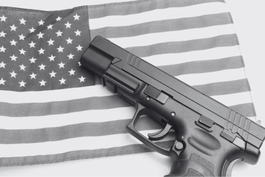 Black-and-white photo of a handgun resting on an American flag, symbolizing gun rights, nationalism, right-wing and Christian domestic terrorism