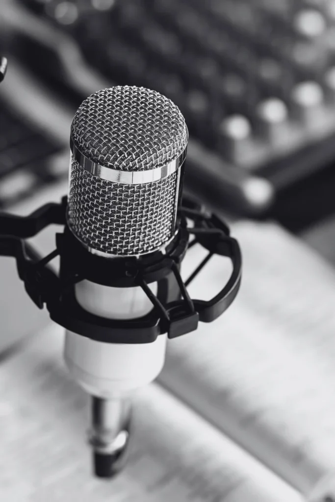 Close-up black-and-white image of a professional microphone with an open book in the background, representing pro-democracy and non-partisan independent media.