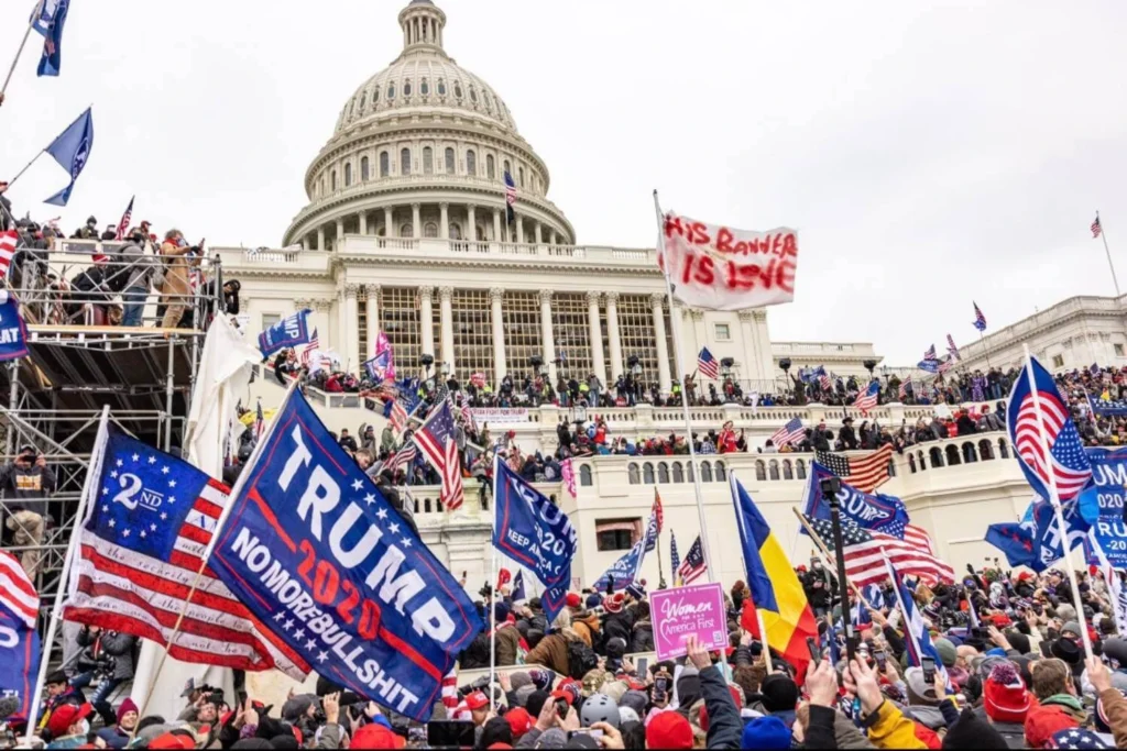 A crowd of Trump supporters waving flags and banners outside the U.S. Capitol on January 6, 2021, during the attempted insurrection that showcased the cult-like devotion of the MAGA movement.
