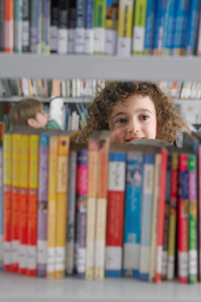 A young child looking through books on a library shelf, symbolizing the importance of giving the next generation access to banned books in America.