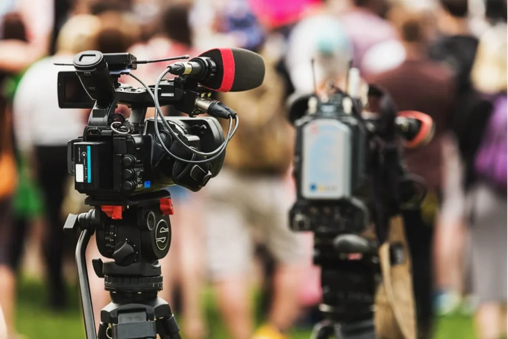 Broadcast news cameras recording a live event, symbolizing independent journalism and the fight for press freedom.
