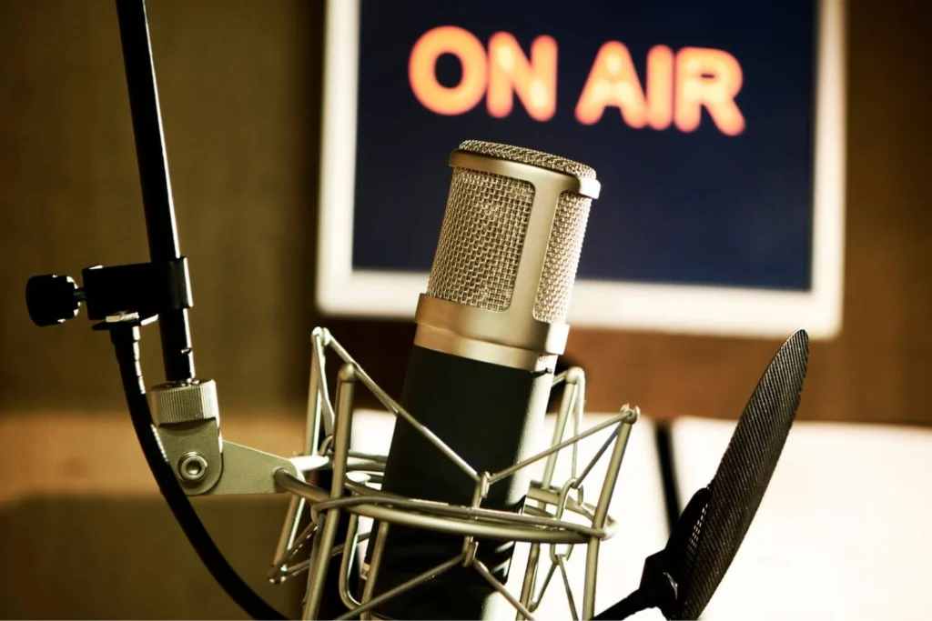 Professional studio microphone with “On Air” sign in background, representing independent radio and podcast journalism.