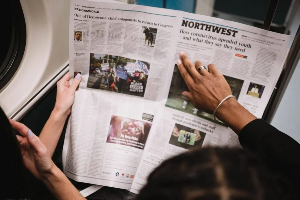 Two women reading a printed newspaper together, representing public trust in journalism and the search for reliable news sources.