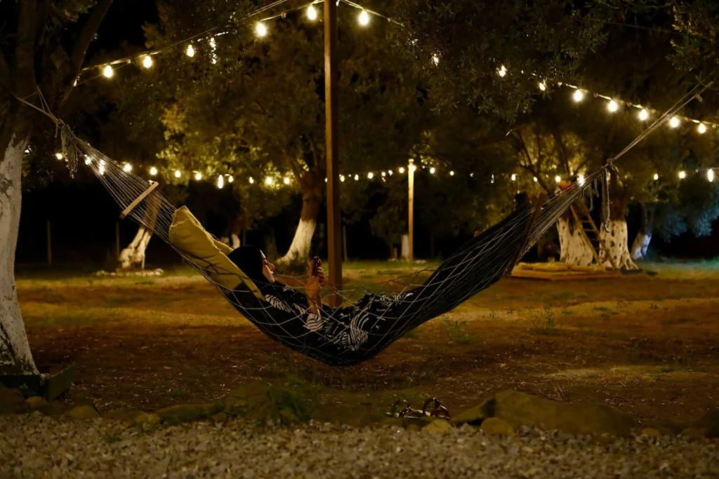 Woman in a hammock under warm string lights at night.