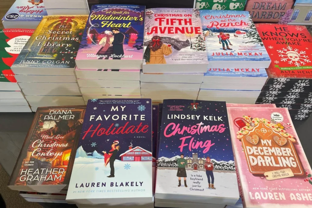 Close-up selection of Christmas romance books stacked on a display table, showing bright and festive cover designs.
