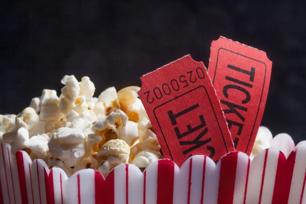Classic red cinema tickets in a striped popcorn tub, symbolizing a cozy movie night experience.