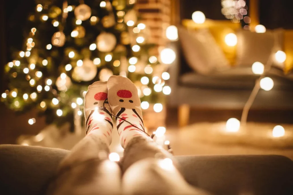 Relaxing Christmas moment with festive socks and glowing tree lights in the background.