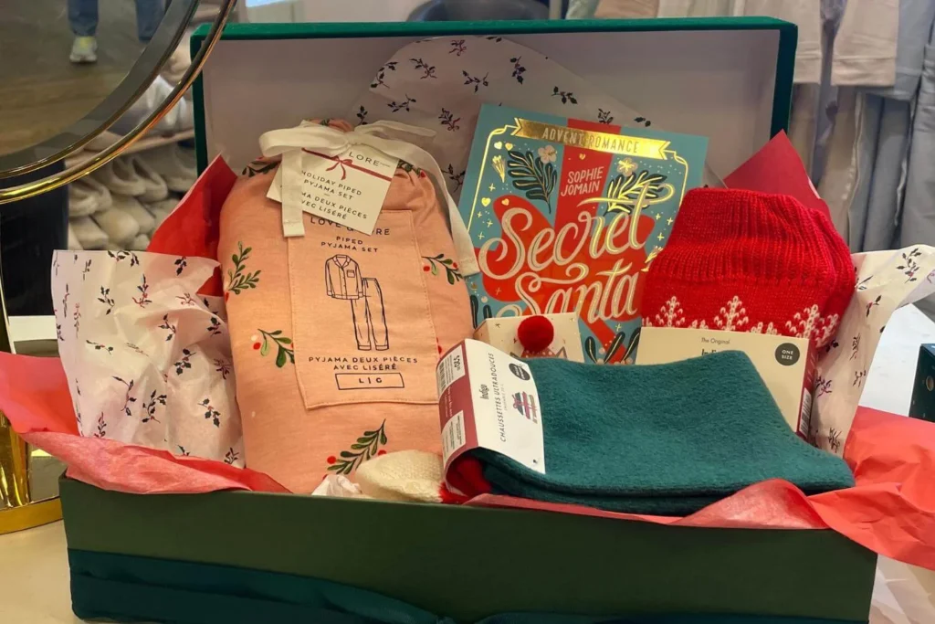 Christmas gift box filled with festive pyjamas, a holiday romance book, cosy socks, and winter-themed treats.