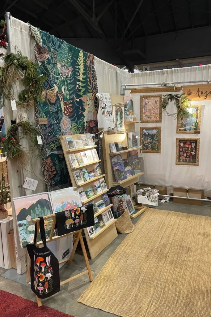 Handmade art prints, cards, and textiles displayed at a local artisan market during winter, highlighting independent makers and small businesses.