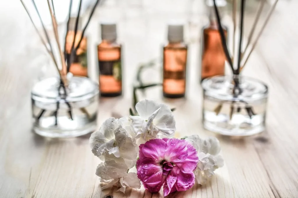 A reed diffuser surrounded by white and pink flowers, creating a relaxing spa-like scent reminiscent of tropical and floral destinations.
