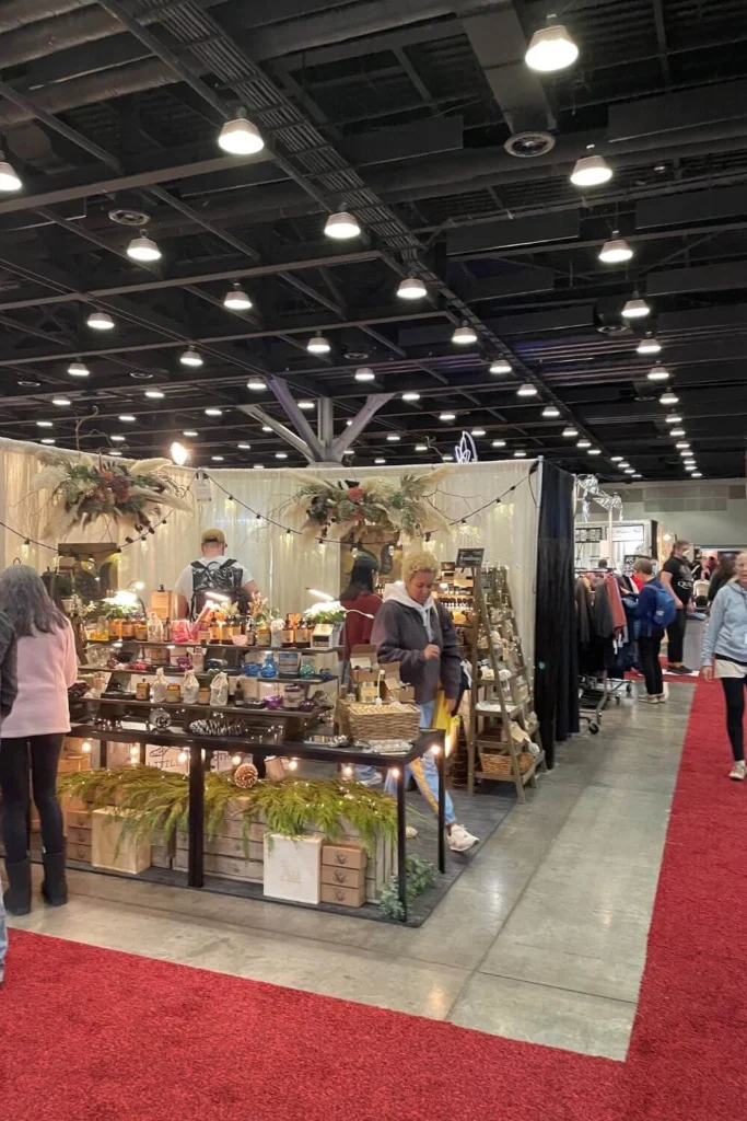 A winter craft market with local artisan stalls, handmade products, festive decorations, and shoppers browsing seasonal gifts.