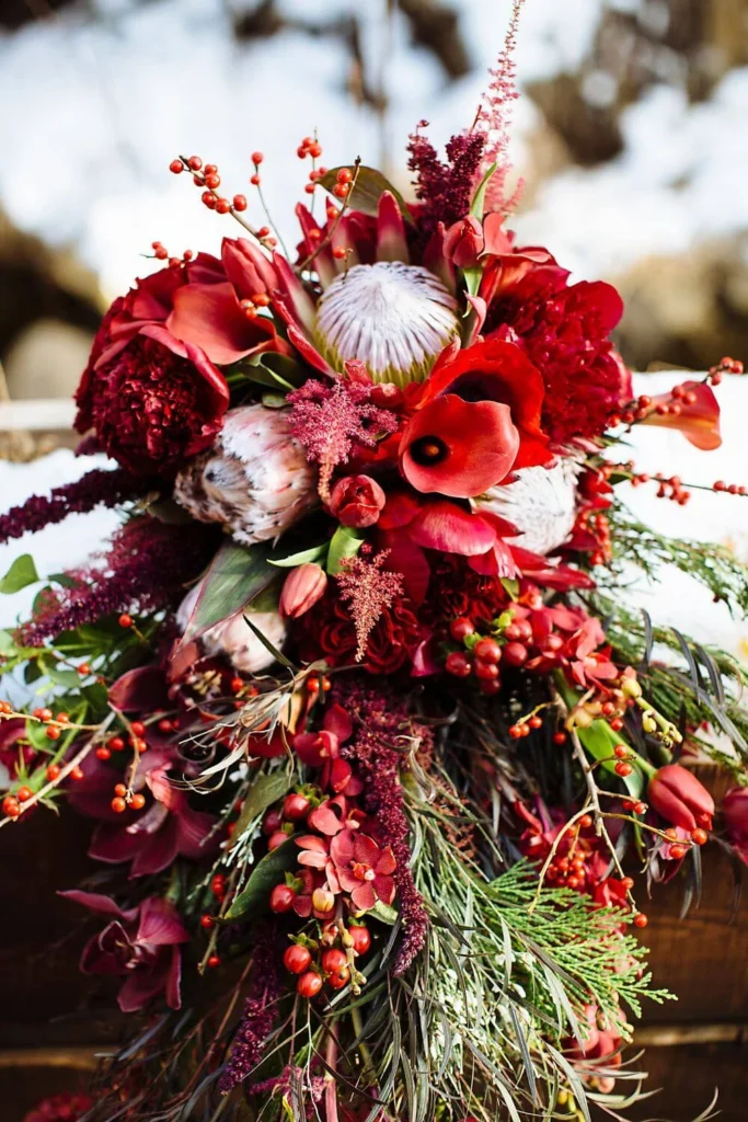 A lush winter floral bouquet with red blooms, berries, and greenery, creating a rich seasonal arrangement perfect for brightening a home in winter.