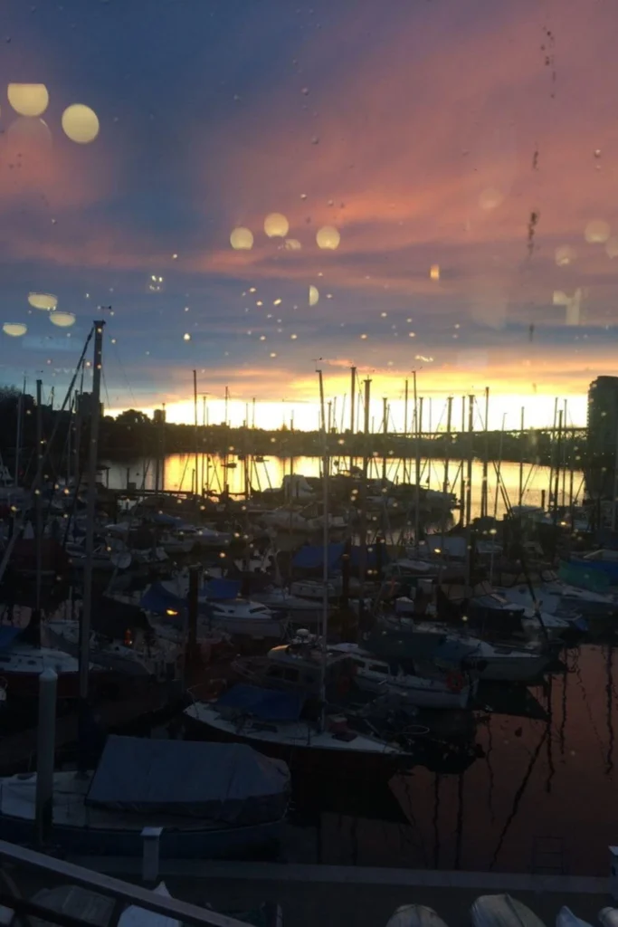 A colourful winter sunset reflecting over a Vancouver marina, with boats and masts silhouetted against the glowing sky.