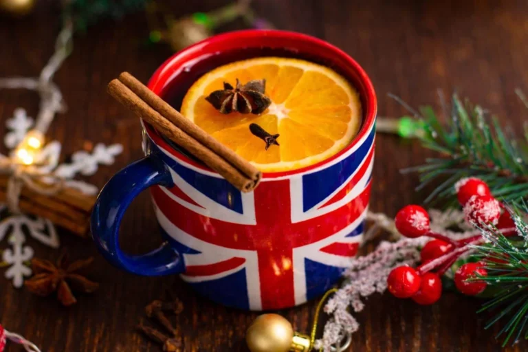 Union Jack mug filled with a warm British Christmas drink, garnished with orange and spices on a festive table.