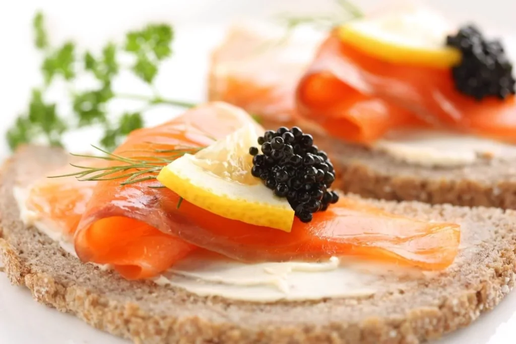 Smoked salmon served on bread with cream cheese, lemon, dill, and caviar as a festive British Christmas appetizer. 
