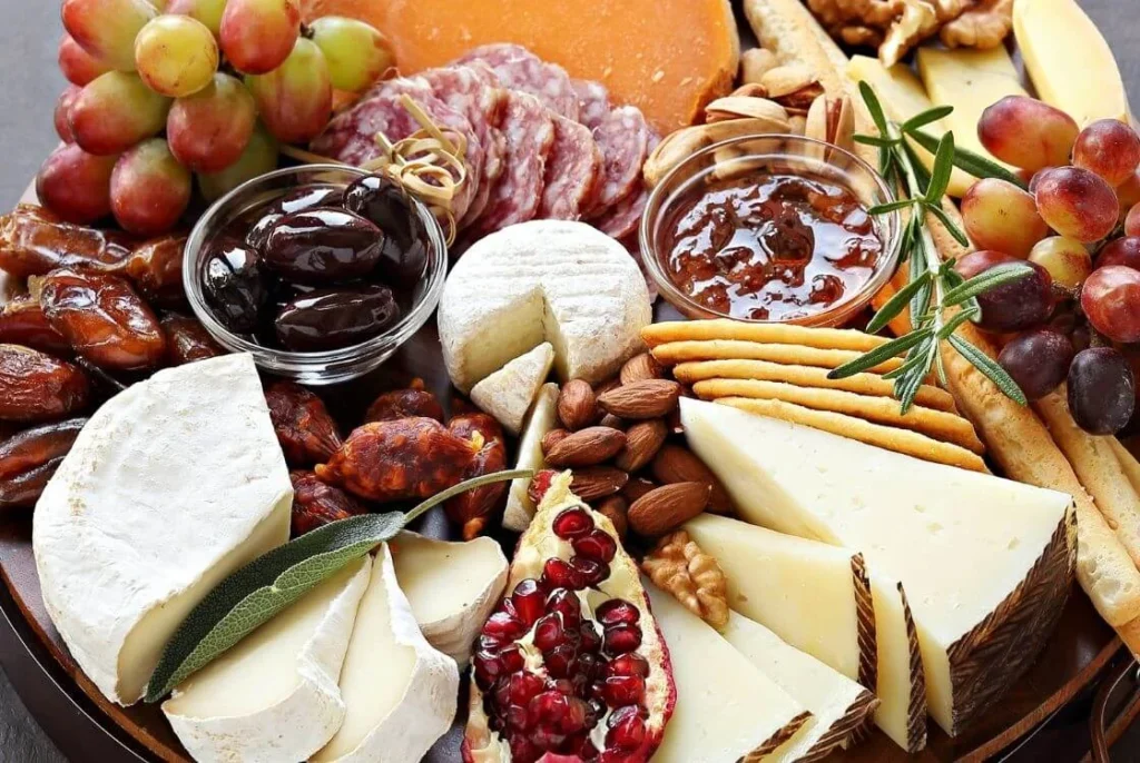 Festive British cheese platter with cheeses, crackers, grapes, chutney, nuts, and cured meats served as Christmas appetizers and snacks.