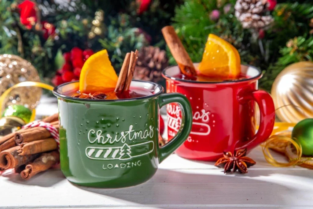 Two mugs of British mulled wine with orange slices and cinnamon sticks.