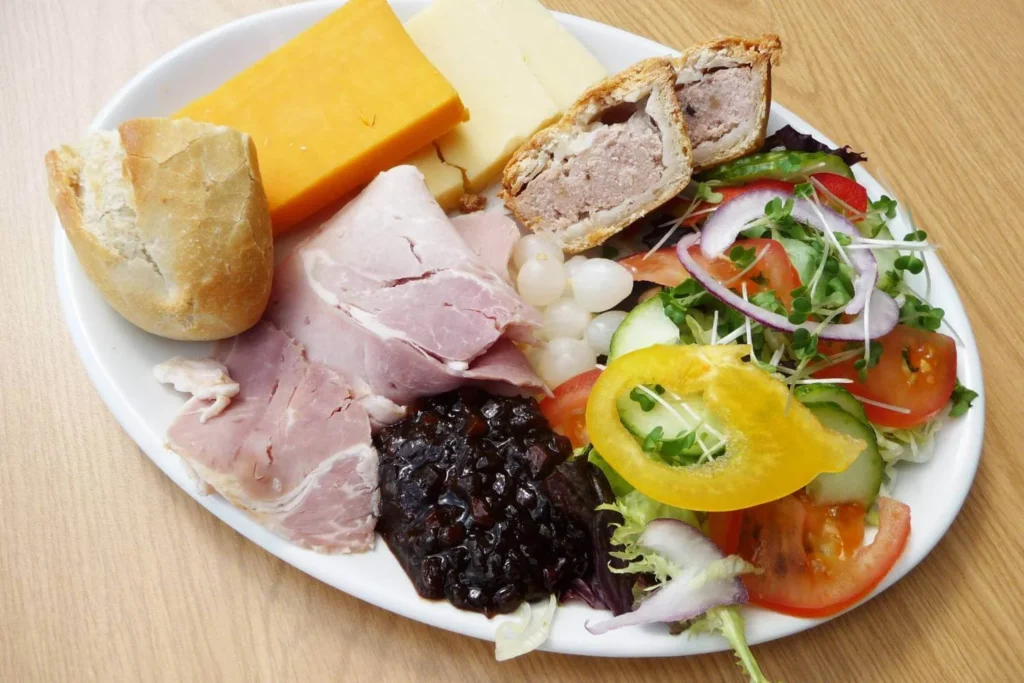 Traditional British ploughman’s lunch with ham, cheese, bread, chutney, and salad served as a festive Christmas platter. 