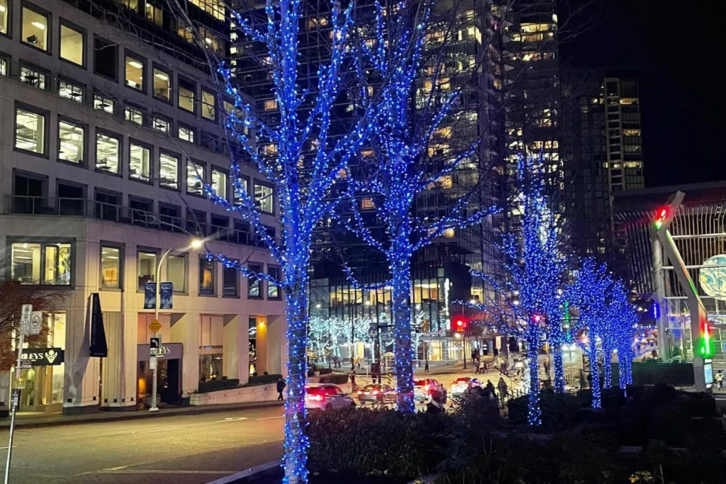 Blue Christmas lights along a downtown Vancouver street near Canada Place at night.