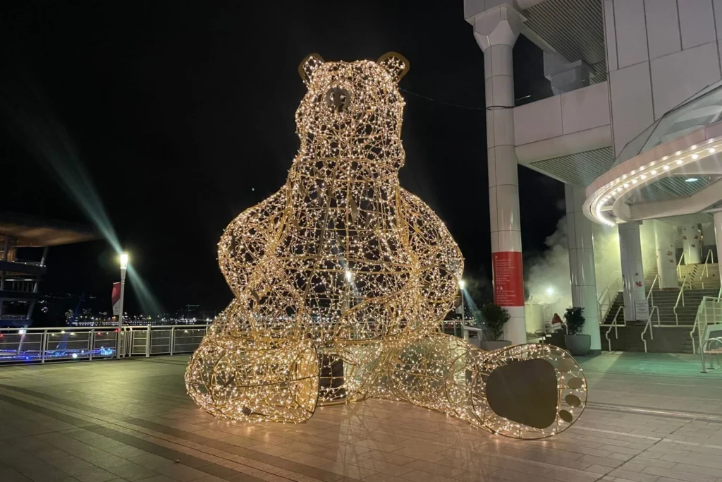 Large illuminated bear sculpture on the waterfront at Canada Place in Vancouver, glowing with festive lights during the holiday season.
