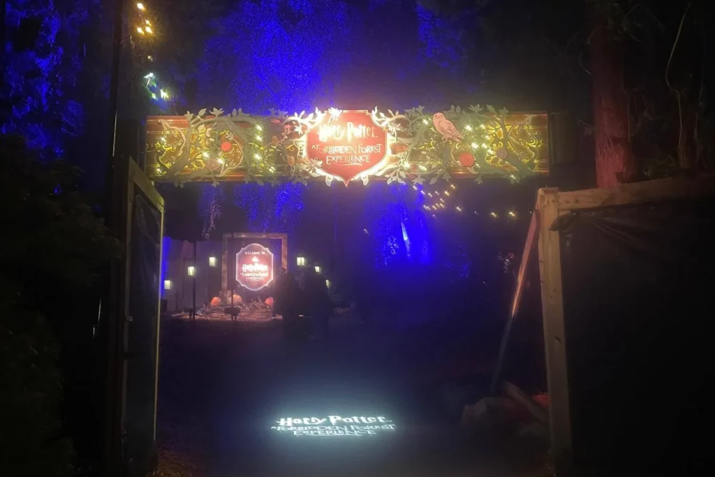 A decorative archway lit with warm lights marking the entrance to the Harry Potter Forbidden Forest Experience.