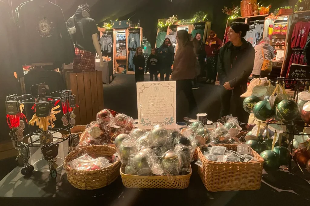 Shoppers browsing Harry Potter themed ornaments and souvenirs inside the Forbidden Forest Experience gift shop tent.
