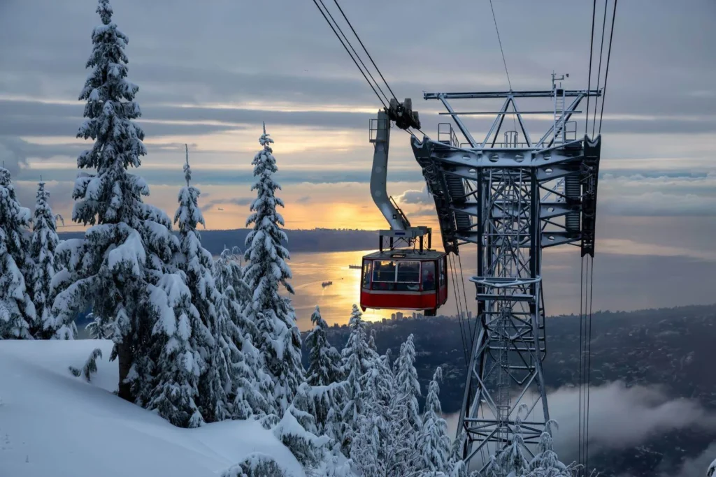Grouse Mountain gondola rising above snow-covered trees with winter views over Vancouver.