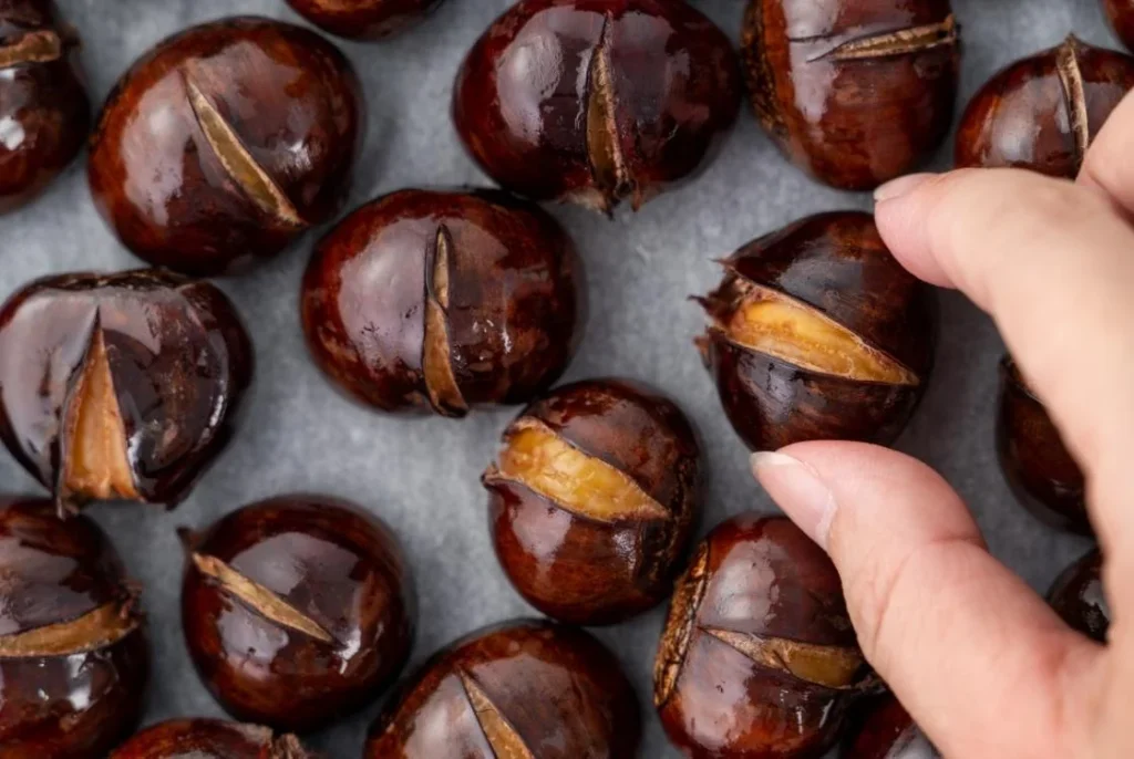 Roasted chestnuts with cracked shells, a classic British Christmas snack often enjoyed in winter.