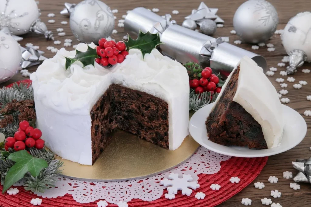 Traditional British Christmas cake covered in white icing and decorated with holly.