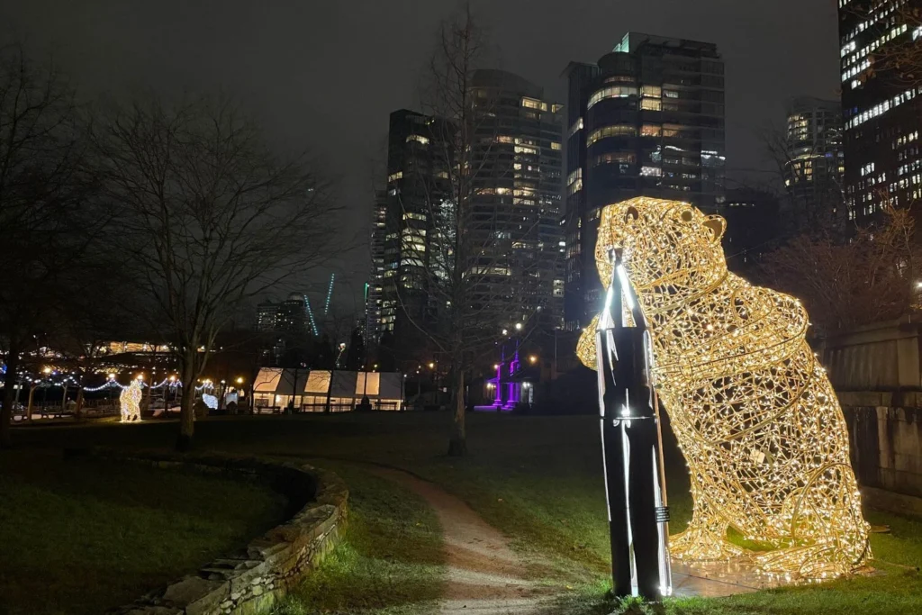 Large illuminated beaver sculpture in Coal Harbour at night, with downtown Vancouver’s high-rises glowing in the background.