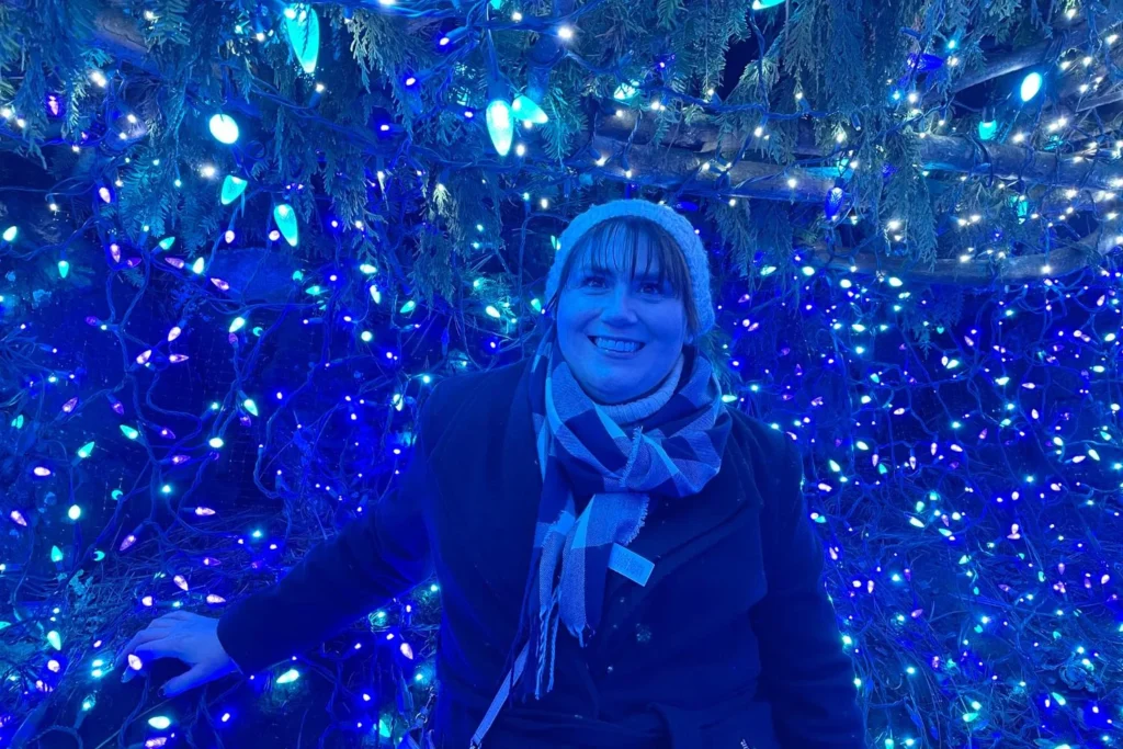 Gemma Lawrence standing inside a tunnel of blue Christmas lights at VanDusen Festival of Lights.