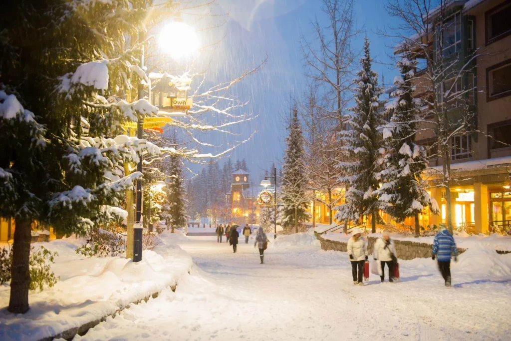 Snowy Whistler Village at night during winter, showing festive lights, pedestrians, and a lively winter festival atmosphere in Canada.