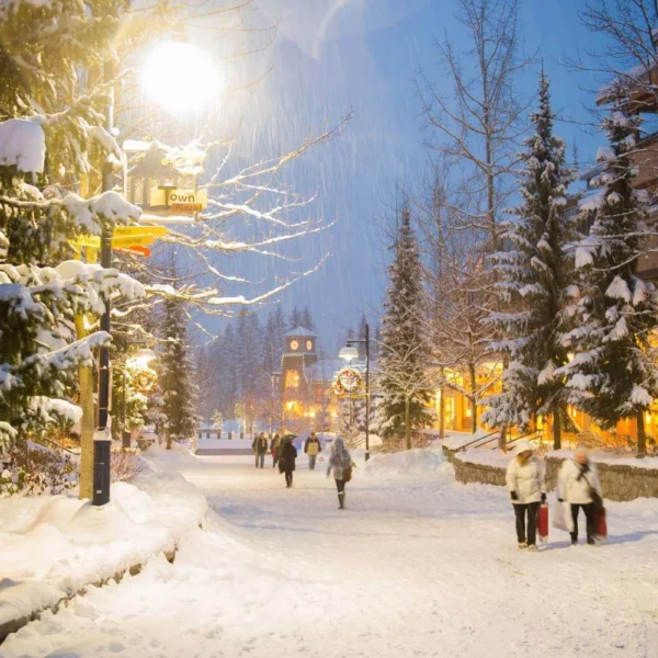 Snowy Whistler Village at night during winter, showing festive lights, pedestrians, and a lively winter festival atmosphere in Canada.