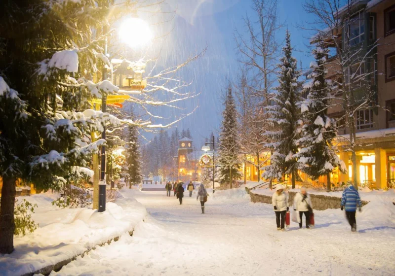 Snowy Whistler Village at night during winter, showing festive lights, pedestrians, and a lively winter festival atmosphere in Canada.