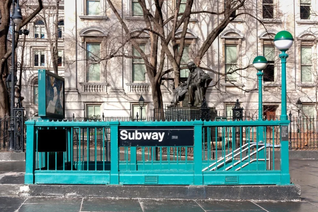 Urban subway entrance with stairs leading underground in a public city space near government buildings.